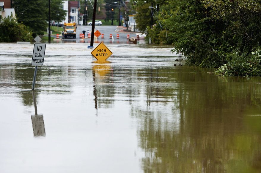 SIGN OF THE TIMES: Water Street sits under several feet of floodwater at Pennsylvania Avenue on Thursday. Several days of heavy rains from the remnants of Tropical Storm Lee followed Hurricane Irene to cause flooding. (T.J. Kirkpatrick/The Washington Times)