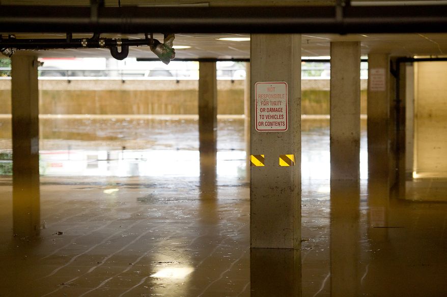 A sign reading "Not responsible for theft or damage to vehicles or contents" is seen in the basement parking lot at Alexandria Tech Center 4 on Eisenhower Avenue in Alexandria, Va., on Sept. 9, 2011. The lot was flooded after heavy rains pounded the region the previous night. (Andrew Harnik/The Washington Times)