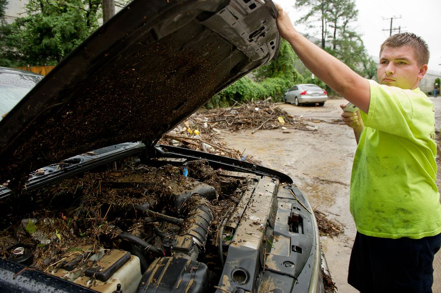 Tow truck driver Terry Walker takes photos of a vehicle's muddy engine on Eisenhower Avenue in Alexandria, Va., on Sept. 9, 2011, after heavy rains pounded the region the previous night. (Andrew Harnik/The Washington Times)