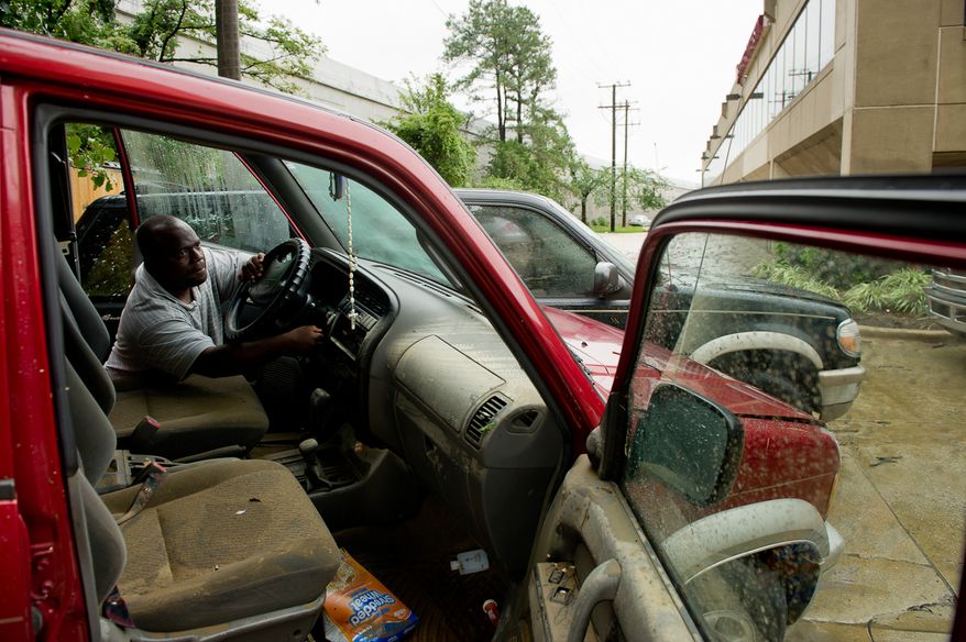 Addison Edward, of Alexandria, Va., attempts to start his friend's Isuzu Trooper on Eisenhower Avenue in Alexandria on Sept. 9, 2011. The vehicle was flooded after heavy rains pounded the region the previous night. (Andrew Harnik/The Washington Times)