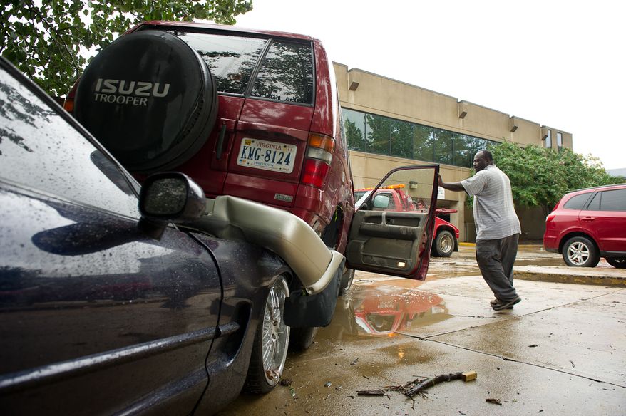 Addison Edward, of Alexandria, Va., closes the door to his friend's Isuzu Trooper on Eisenhower Avenue in Alexandria on Sept. 9, 2011. The vehicle was flooded after heavy rains pounded the region the previous night. (Andrew Harnik/The Washington Times)
