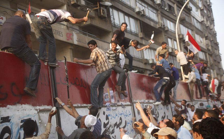 Some hundreds of Egyptian activists demolish a concrete wall around a building housing the Israeli embassy in Cairo, Egypt, to protect it against demonstrators, Friday, Sept. 9, 2011. (AP Photo/Amr Nabil)