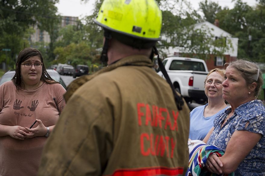 Huntington neighborhood residents Porter Wiseman (left), Nancy Foote (second from right) and Meredith Ellsworth (right) talk Sept. 9, 2011, with a Fairfax County official, as they and other residents attempt to clean up from the flooding on Arlington Terrace in the Huntington neighborhood of Alexandria, Va. (Rod Lamkey Jr./The Washington Times)