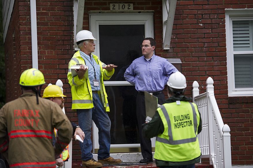 Dan Chavka talks Sept. 9, 2011, with building inspectors on his front porch as he and other residents attempted to clean up from the flooding on Arlington Terrace in the Huntington neighborhood of Alexandria, Va., after heavy rains pounded the region. (Rod Lamkey Jr./The Washington Times)
