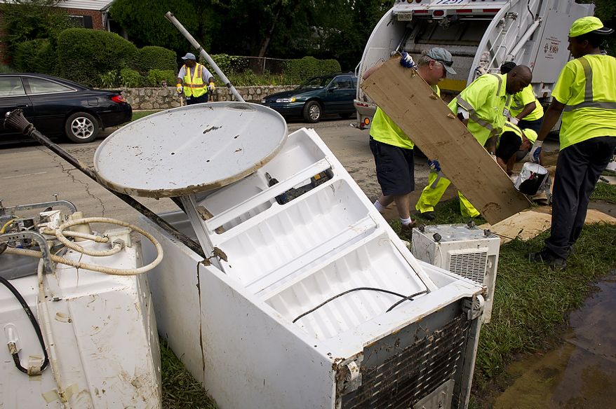 A clean-up crew removes debris and discarded belongings on Sept. 9, 2011, as residents cleaned up from the flooding on Arlington Terrace in the Huntington neighborhood of Alexandria, Va., after heavy rains pounded the region. (Rod Lamkey Jr./The Washington Times)