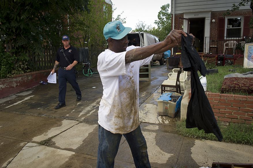 Titus Boyd looks through a basket of flood-damaged belongings from his parents' house on Sept. 9, 2011, as residents cleaned up from the flooding on Arlington Terrace in the Huntington neighborhood of Alexandria, Va., after heavy rains pounded the region. (Rod Lamkey Jr./The Washington Times)