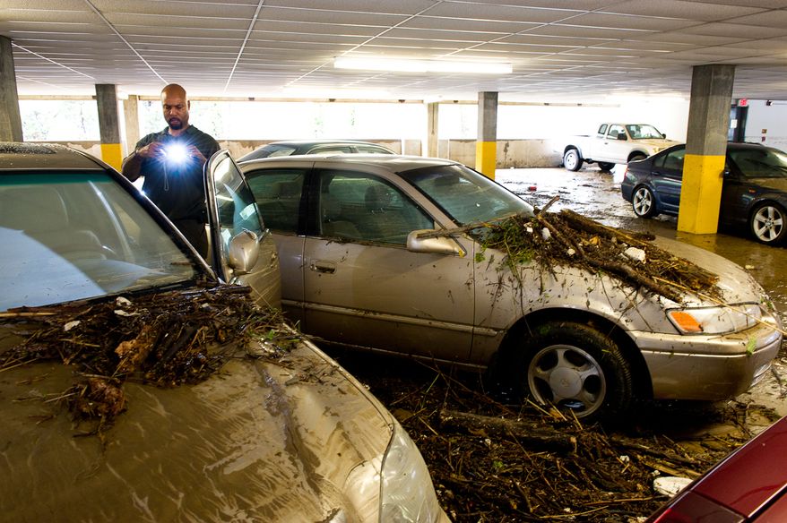 William Borden takes photographs of the flood damage to his Lexus in the parking lot of Strayer University in Alexandria, Va., on Sept. 9, 2011. The lot was flooded after heavy rains pounded the region the previous night. (Andrew Harnik/The Washington Times)