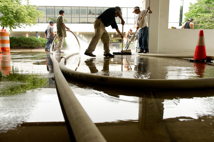 A cleaning crew removes mud from the first-floor parking lot at Alexandria Tech Center II on Eisenhower Avenue in Alexandria, Va., on Sept. 9, 2011. The lot was flooded after heavy rains pounded the region the previous night. (Andrew Harnik/The Washington Times)