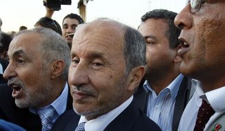 ** FILE ** Libyan Transitional National Council chairman Mustafa Abdul-Jalil (center), flanked by bodyguards, arrives at Metiga Airport in Tripoli, Libya, on Saturday, Sept. 10, 2011. (AP Photo/Francois Mori)