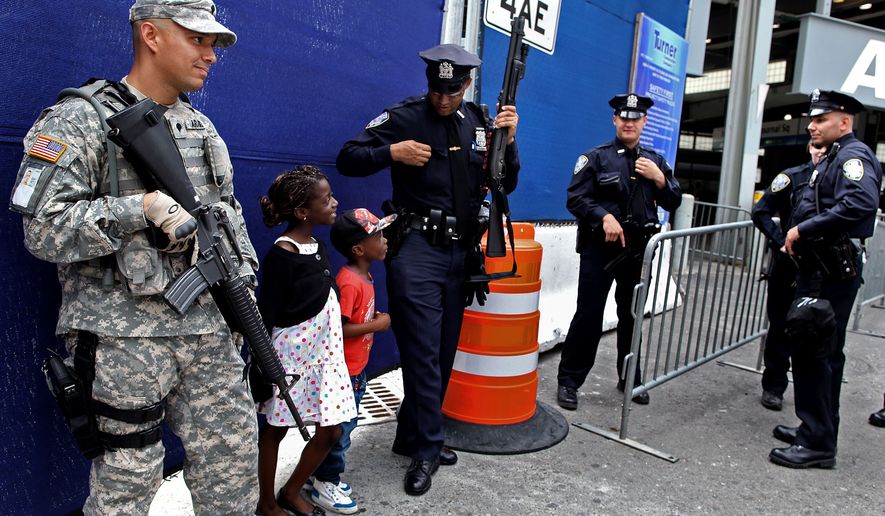 A Port Authority police officer shares a light moment with children visiting from France at commuter train station near ground zero Saturday, Sept. 10, 2011, in New York. Heavily armed police remained a visible presence around New York on the eve of the 10th anniversary of the World Trade Center attacks. (AP Photo/Craig Ruttle)