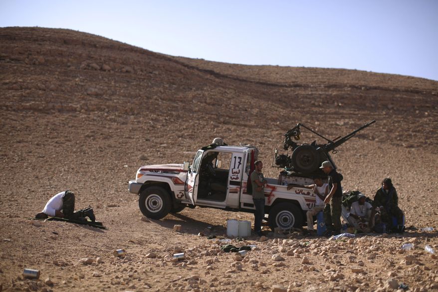 Rebel fighter Ahmed Hamza (left), a 23-year-old former engineering student, prays on the outskirts of Bani Walid, Libya, on Sunday, Sept. 11, 2011. Libyan fighters are signing up for a final assault on one of the last remaining bastions of support for Col. Moammar Gadhafi. (AP Photo/Alexandre Meneghini)