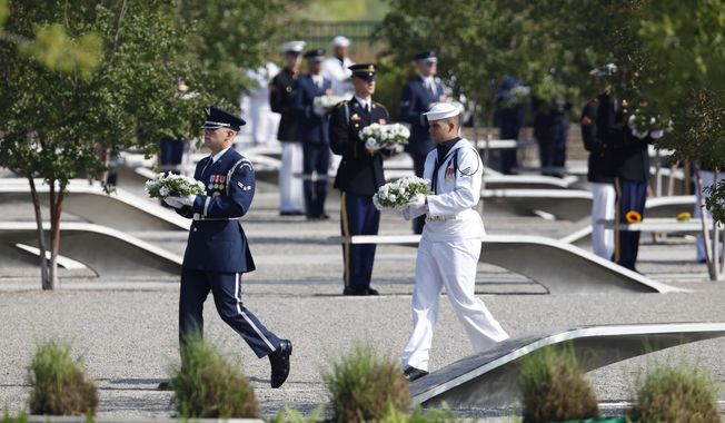 An honor guard carries wreaths at the Pentagon Memorial outside the Defense Department headquarters in Arlington on Sunday, Sept. 11, 2011, to mark the 10th anniversary of the 9/11 attacks. (AP Photo/Charles Dharapak)