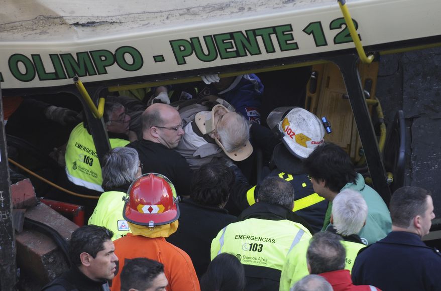A wounded passenger is carried out of a train after it crashed in Buenos Aires on Tuesday, Sept. 13, 2011. At least seven people were killed and 162 injured in the rush-hour crash, which involved two passenger trains and the bus, the driver of which drove around barriers in an attempt to beat the trains, Argentine authorities said. (AP Photo/Rodolfo Pezzoni, DyN)