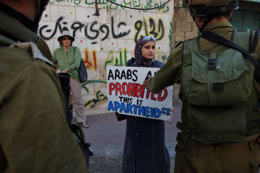 Israeli soldiers face Palestinian activists during a demonstration Wednesday against the closure of Al-Shuhada Street in the West Bank city of Hebron. Protesters had symbolically renamed the street "Apartheid Street." (Associated Press)