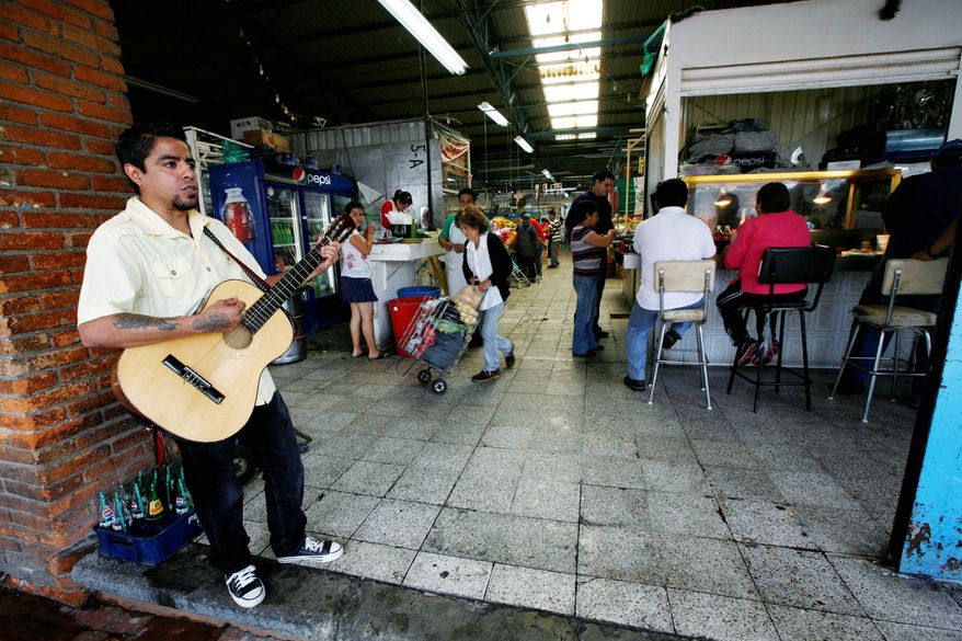 A musician plays at the entrance to the Gascasonica neighborhood market, one of many in Mexico City that are losing customers to foreign-owned chains. (Associated Press)