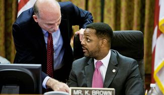D.C. Council member Phil Mendelson confers with council Chairman Kwame R. Brown on Tuesday.  Mr. Mendelson favored the income-tax increase; Mr. Brown opposed it. (T.J. Kirkpatrick/The Washington Times)