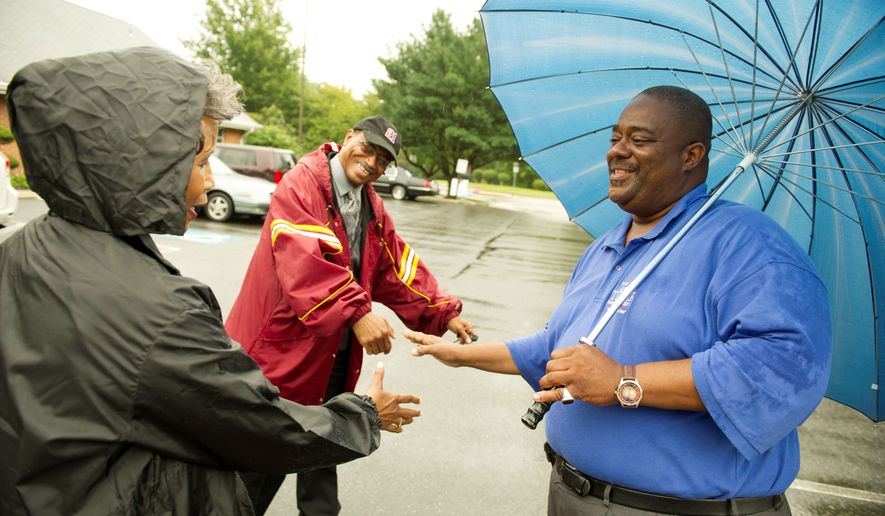 Candidate Arthur Turner (right) greets voters Ricardo Lewis and his wife Sandra Livingston-Lewis (left) of Mitchellville, who arrived in the rain to vote. (Rod Lamkey Jr./The Washington Times)