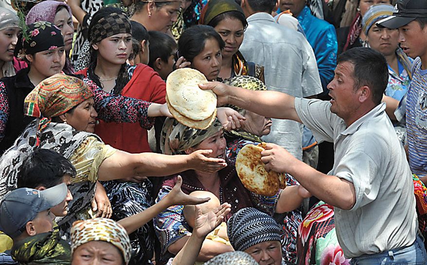 **FILE** Uzbek emergency workers and volunteers pass traditional flat bread to ethnic Uzbek refugees from Kyrgyzstan near the Uzbek village of Jalal-Kuduk on June 14, 2010. (Associated Press)