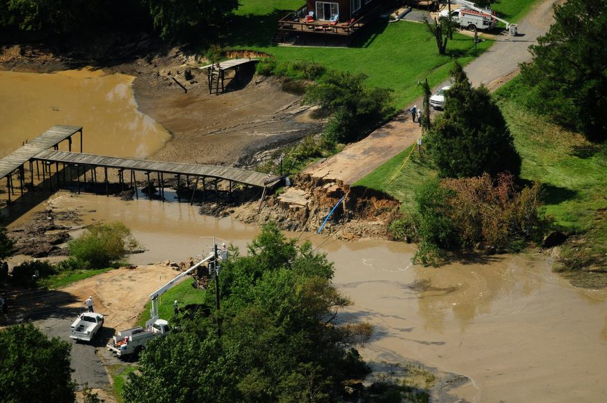 People assess the damage Friday, Sept. 9, 2011, after heavy rainfall on Thursday knocked out Mattox Avenue, opening up Placid Lake into Burnt House Cove in Oak Grove, Va., due to the effects of the remnants of Tropical Storm Lee. (AP Photo/The Free Lance-Star, Dave Ellis)