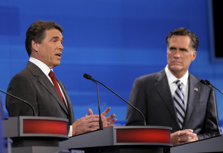 Former Massachusetts Gov. Mitt Romney (right) listens as Texas Gov. Rick Perry makes a statement during a Republican presidential candidate debate on Sept. 22, 2011, in Orlando, Fla. (Associated Press)