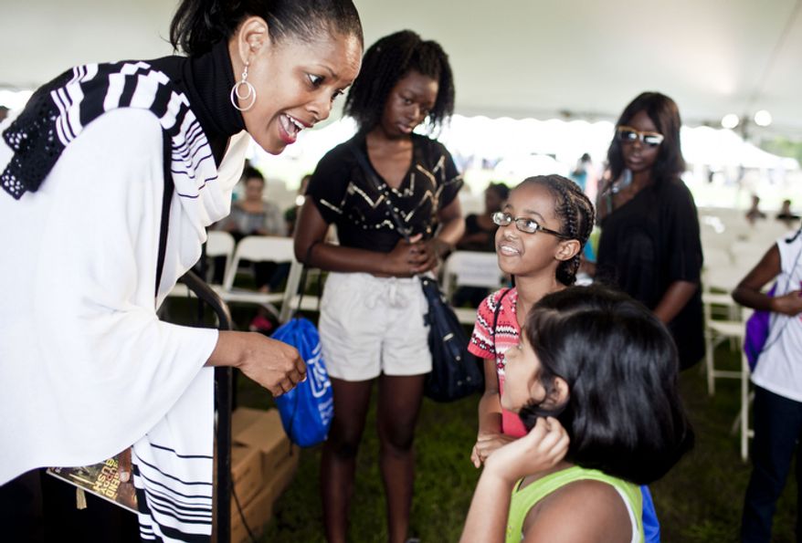 Shelia P. Moses, left, an author for young readers, greets Samra Beyene, 11, center in glasses, of Haymarket, Va., and Nikita Rao, 7, of Herndon, Va., after speaking during the National Book Festival.
(T.J. Kirkpatrick/ The Washington Times)