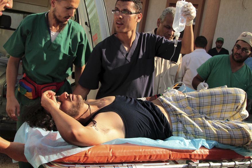 Medics carry a wounded revolutionary fighter to a field hospital in Sirte, Libya, on Saturday, Sept. 24, 2011. Backed by rockets and heavy artillery, hundreds of Libyan revolutionary fighters pushed into the city, Col. Moammar Gadhafi's hometown, from the west in the first significant assault in about a week. (AP Photo/Gaia Anderson)