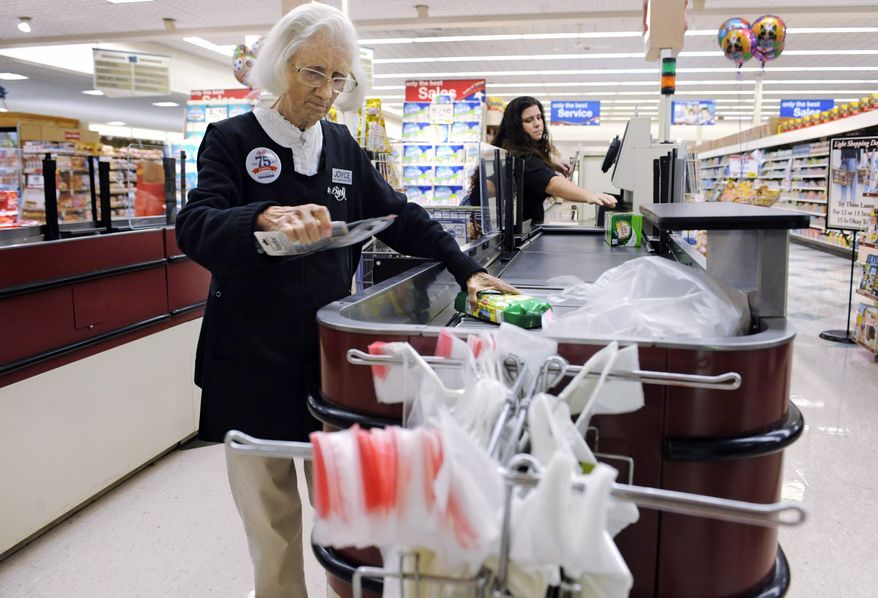 ** FILE ** Cashier Joyce Mackie bags groceries as a customer uses a self-service checkout station at a Big Y supermarket in Manchester, Conn. (Associated Press)