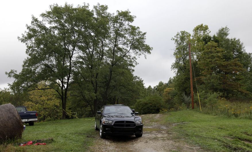 On Monday, Sept. 26, 2011, a police officer sits in an unmarked car at the entrance to the site near Laurel, Ind., in rural Franklin County where five people were found dead. (AP Photo/A.J. Mast)