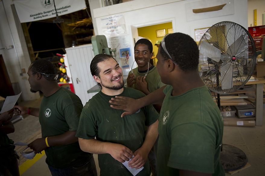 Darel Bellamy (right) shares a light moment with his cousin Maurice White (center) and Samuel Morrill (left) on pay day at the Alexandria Seaport Foundation in Alexandria, Va., Thursday, August 4, 2011. Located on the waterfront in Old Town Alexandria, the Alexandria Seaport Foundation is a non-profit paid apprenticeship and hands-on educational program which serves at-risk youths ages 17-21. In the program these youths learn life skills, team work and building their self esteem. In the program apprentices learn carpentry skills and planing for career paths, in addition to earning their GED right here. The ASF says that it costs $100,000.00 to detain a juvenile for a year in Virginia, but only $15,000.00 to educate and place an ASF apprentice. The paid staff and numerous volunteers teaches approximately 8-16 students, however today they are working with around 10. The program lasts 5 to 8 months. Every Tuesday night is "Open Shop" a time when the shop is open to the public. (Rod Lamkey Jr/The Washington Times)