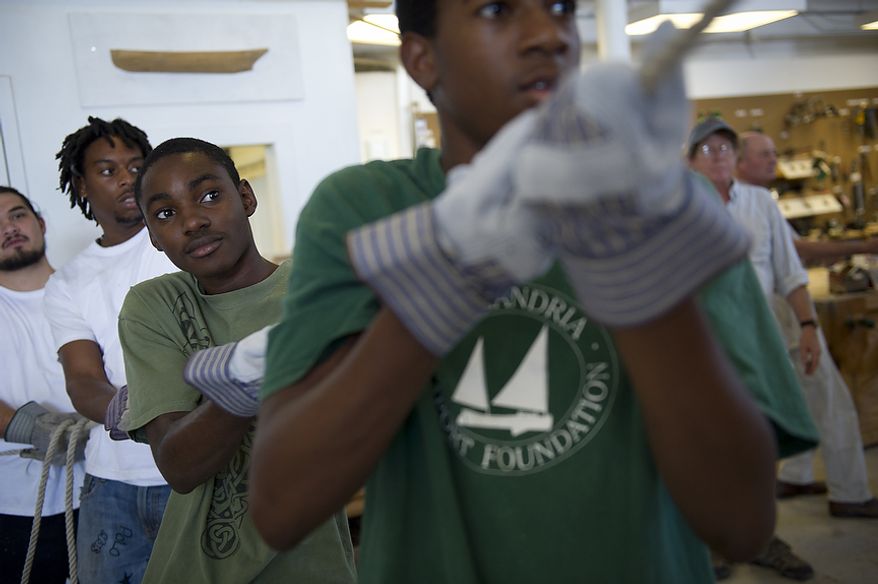 Apprentices Maurice White (left) Darren Walters (second from right) Priestly Williams (second from left) and Samuel Morrill (left) work together flipping the dory boat at the Alexandria Seaport Foundation in Alexandria, Va., Thursday, August 11, 2011. Located on the waterfront in Old Town Alexandria, the Alexandria Seaport Foundation is a non-profit paid apprenticeship and hands-on educational program which serves at-risk youths ages 17-21. In the program these youths learn life skills, team work and building their self esteem. In the program apprentices learn carpentry skills and planing for career paths, in addition to earning their GED right here. The ASF says that it costs $100,000.00 to detain a juvenile for a year in Virginia, but only $15,000.00 to educate and place an ASF apprentice. The paid staff and numerous volunteers teaches approximately 8-16 students, however today they are working with around 10. The program lasts 5 to 8 months. Every Tuesday night is "Open Shop" a time when the shop is open to the public. (Rod Lamkey Jr/The Washington Times)