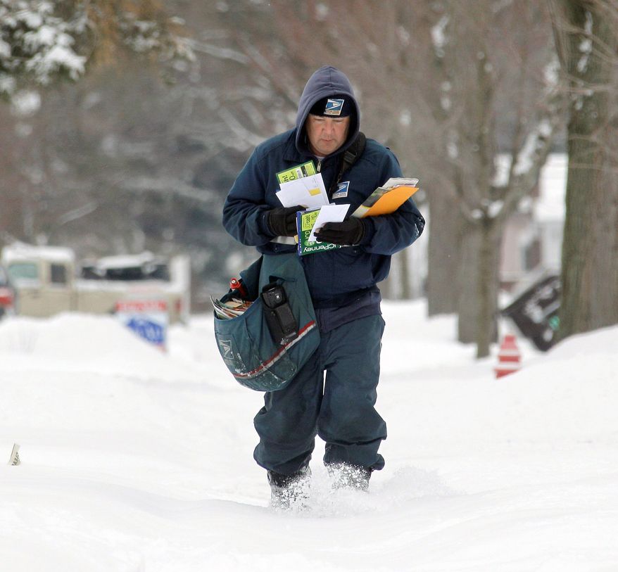 **FILE** A Postal Service letter carrier delivers mail in the snow in Berea, Ohio. (Associated Press)