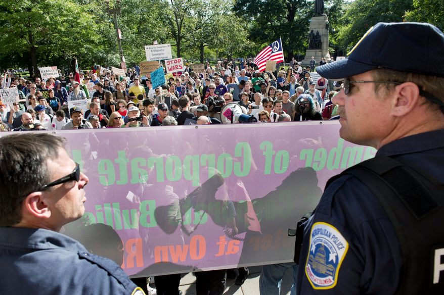 A police line stands in front of the D.C. Chamber of Commerce building in Northwest as protesters rally over a variety of issues. (Andrew Harnik / The Washington Times)