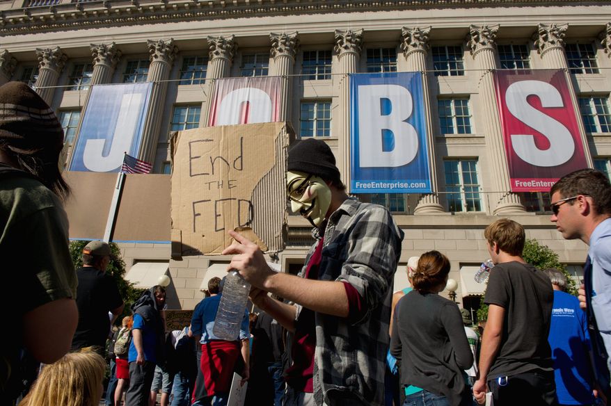 Barry Freed wears a mask of 17th-century Gunpowder Plotter Guy Fawkes in a protest Thursday outside the Chamber of Commerce. (Andrew Harnik / The Washington Times)