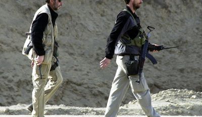 ** FILE ** Two men with U.S. special operations forces walk nearby as the Northern Alliance troops fight pro-Taliban forces in the fortress near Mazar-e-Sharif in northern Afghanistan in 2001. (AP Photo/Darko Bandic, File)
