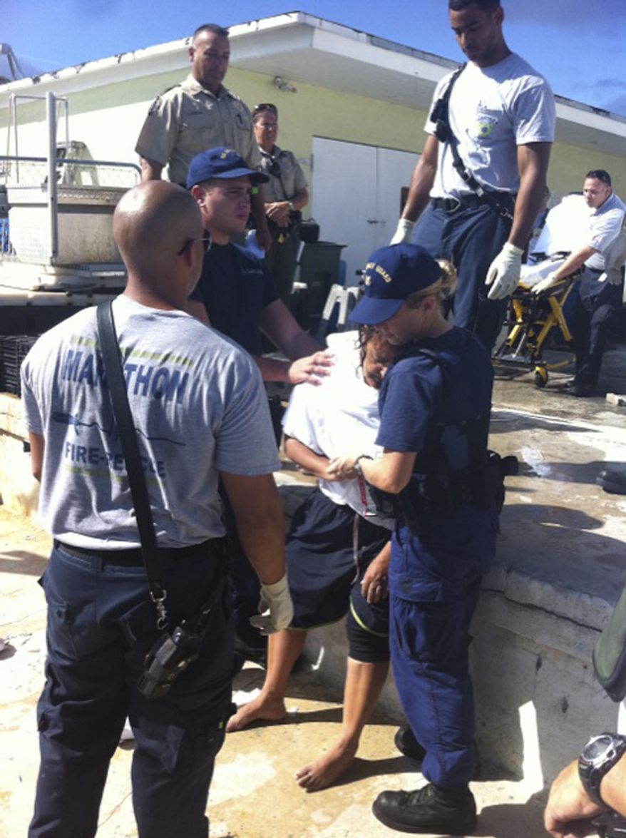 U.S. Coast Guard Seaman Kendra Graves (right) and Petty Officer 3rd Class Robert Femia assist EMS personnel in Marathon, Fla., with one of seven boaters rescued on Sunday, Oct. 9, 2011, after treading water for around 20 hours after their boat capsized and sank. (AP Photo/U.S. Coast Guard)