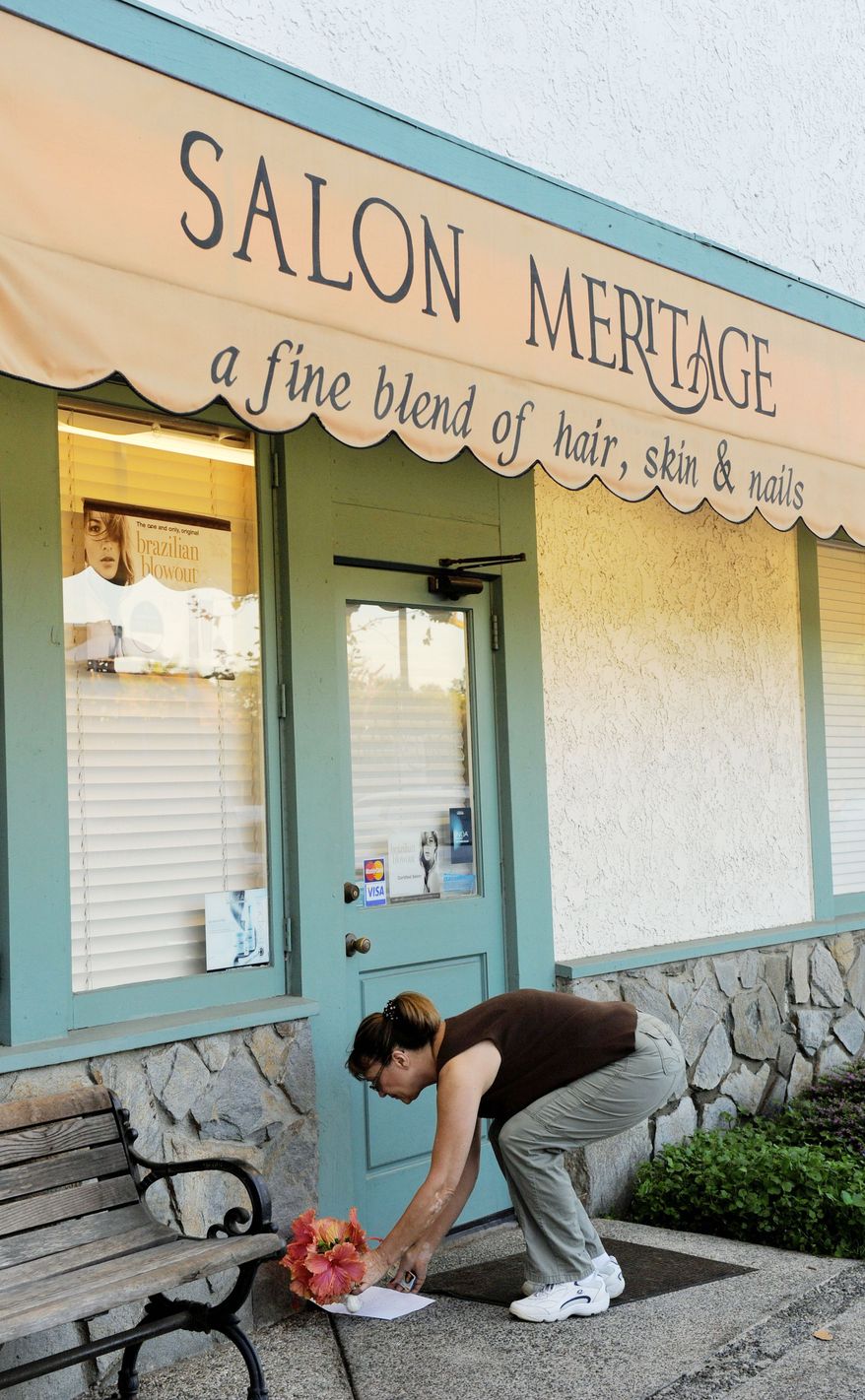 A well-wisher places flowers Thursday in front of the salon in Seal Beach, Calif., where eight people were fatally shot the day before. (Associated Press)