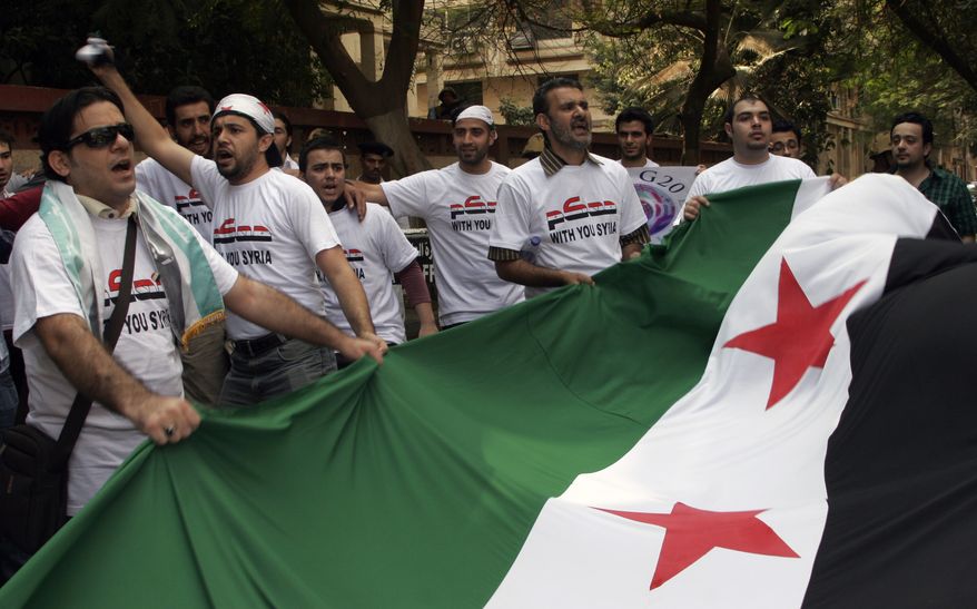Protesters carry a Syrian flag during a demonstration against President Bashar Assad in front of the Syrian Embassy in Cairo on Saturday, Oct. 15, 2011. (AP Photo/Mohammed Abu Zaid)