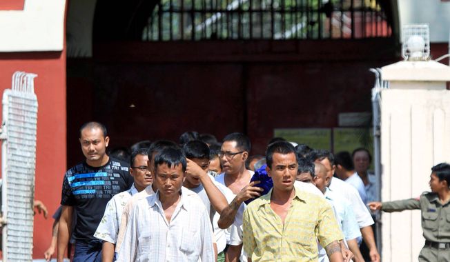 Prisoners walk out of Insein Prison  in Yangon, Myanmar, on Wednesday. The government has begun releasing prisoners but has held back on freeing some prominent political figures. (Associated Press)