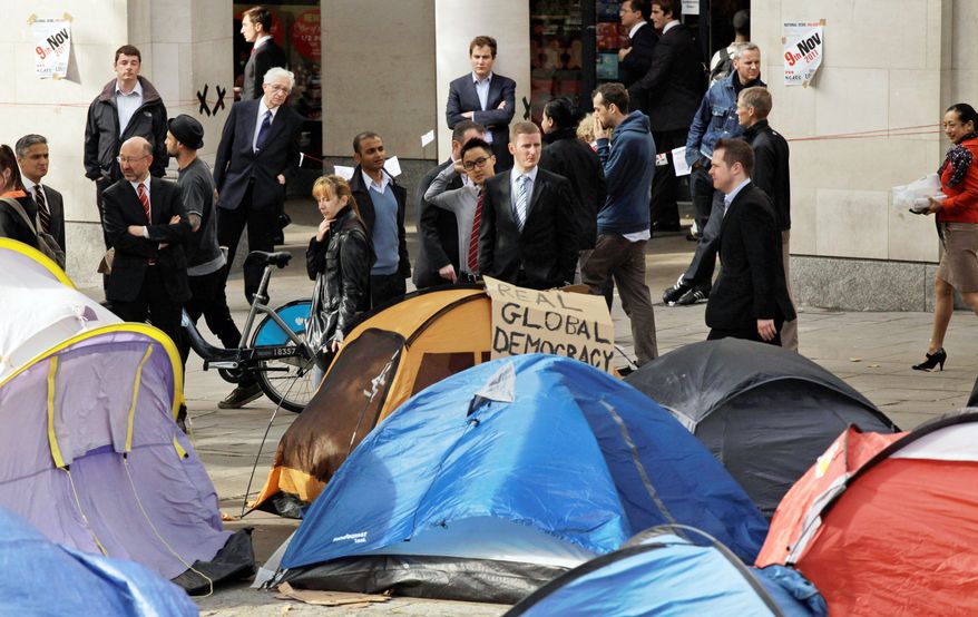 Business people, taking a break during their lunch hour on Monday, look at tents put up by protesters from the "Occupy London Stock Exchange" group as they continue their demonstration that started on Saturday outside St. Paul's Cathedral near the London Stock Exchange. (Associated Press)