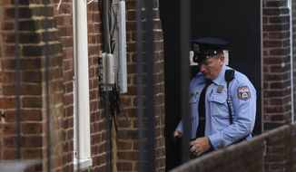 A police officer stands in an alley doorway of an apartment building in Philadelphia on Monday, Oct. 17, 2011,  after the landlord on Saturday discovered four mentally disabled adults locked in the sub-basement of the building. (AP Photo/Matt Rourke)

