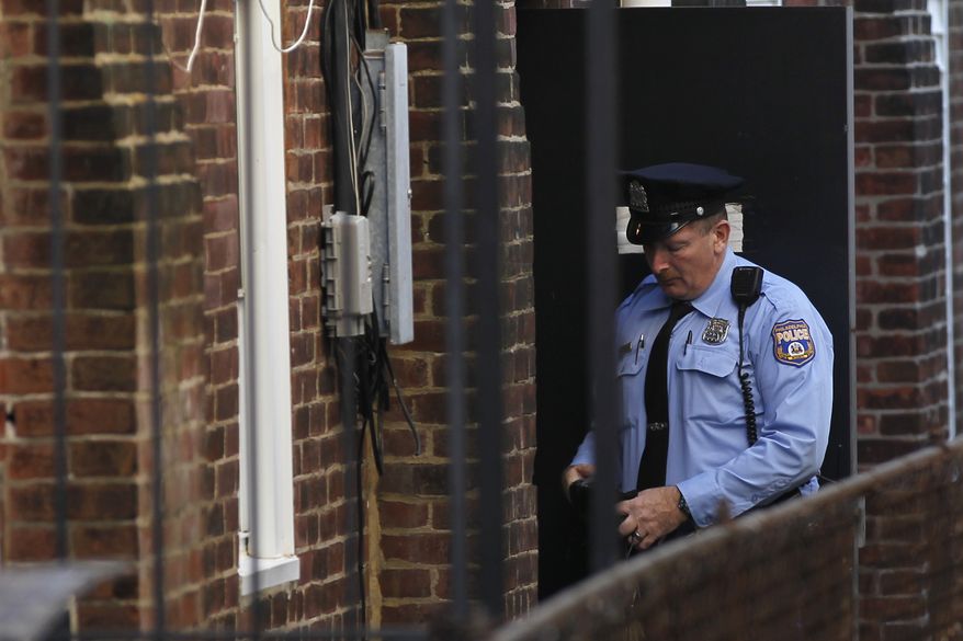 A police officer stands in an alley doorway of an apartment building in Philadelphia on Monday, Oct. 17, 2011, after the landlord on Saturday discovered four mentally disabled adults locked in the sub-basement of the building. (AP Photo/Matt Rourke)