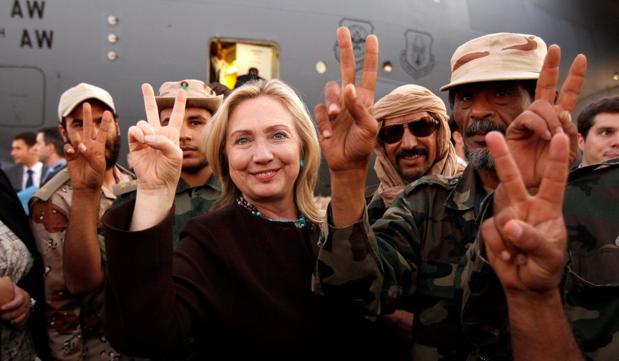 Secretary of State Hillary Rodham Clinton and Libyan freedom fighters signal victory before her departure from Tripoli on Tuesday. (Associated Press)