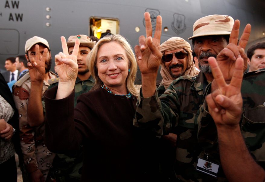 Secretary of State Hillary Rodham Clinton and Libyan freedom fighters signal victory before her departure from Tripoli on Tuesday. (Associated Press)