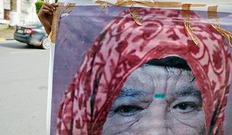 A Libyan man holds a photo of Col. Moammar Gadhafi, manipulated to show the leader dressed as a woman, in Tripoli, Libya, on Oct. 20, 2011. Libya&#39;s information minister said Gadhafi was killed earlier that day when revolutionary forces overwhelmed his hometown of Sirte. (Associated Press)