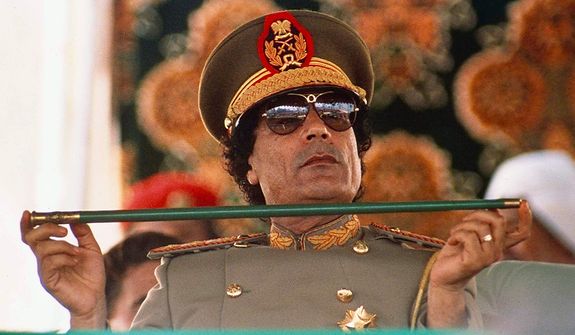 Libyan leader Col. Moammar Gadhafi holds a baton on Sept. 1, 1987, as he sits to review Libyan troops during the 18th anniversary celebration of Libya&#39;s revolution in Tripoli. (Associated Press)