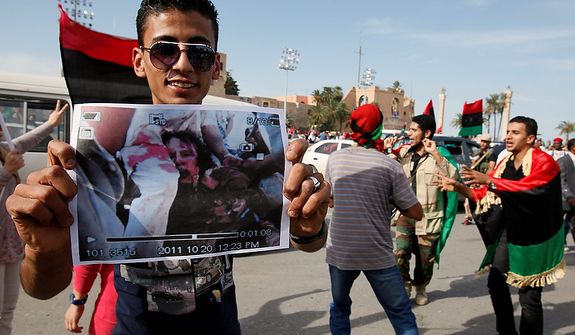 A man holds a photo said to be of the body of Col. Moammar Gadhafi after announcement of the former leader&#39;s death in Tripoli, Libya, on Oct. 20, 2011. (Associated Press)