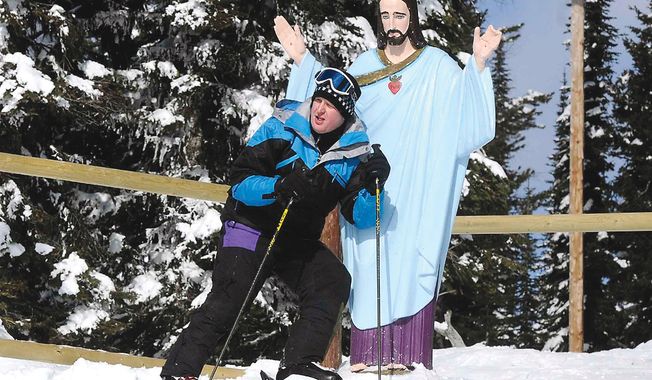 Lyle Burke of the Canadian province of Alberta poses with the statue of Jesus Christ near the top of Chair 2 at the Whitefish Mountain Resort in Montana in February. The statue, erected in 1953 to honor World War II veterans, may have to be removed after the U.S. Forest Service recently denied a special-use permit allowing the stone statue. (AP Photo/The Missoulian, Linda Thompson)