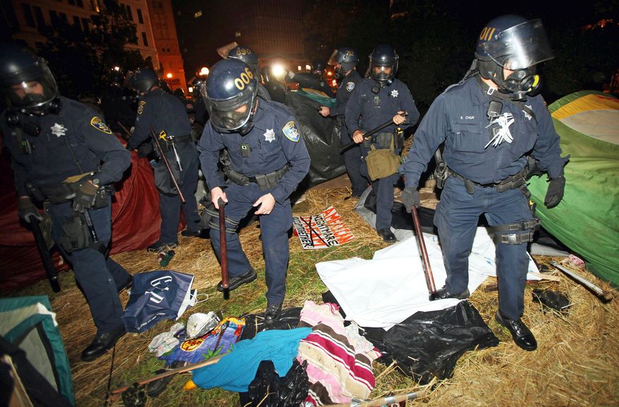 Oakland, Calif., police search tents in Frank Ogawa Plaza as they disperse Occupy Oakland protesters early Tuesday. City officials had been supportive, but later said the protesters were breaking the law and could not stay in the park overnight. (Associated Press)