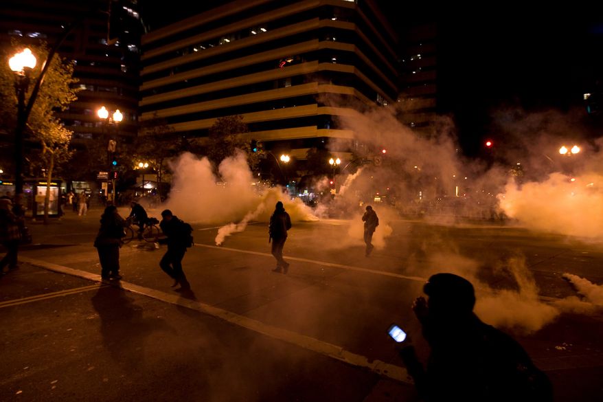 "Occupy Wall Street" protesters run from tear gas deployed by police at 14th Street and Broadway in Oakland, Calif., on Tuesday, Oct. 25, 2011. (AP Photo/Darryl Bush)