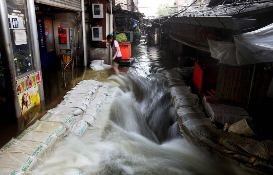 A woman struggles to walk as floodwaters gush through a marketplace Thursday in a riverside neighborhood near Bangkok's Grand Palace, built in the 18th century. Clamoring aboard bamboo rafts and army trucks, residents living on the heavily inundated outskirts of Bangkok fled waterlogged homes as floodwaters moved closer to the heart of the Thai capital. (Associated Press)